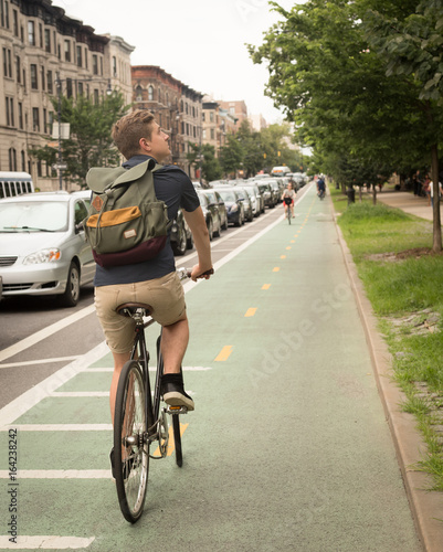 Back view of modern hipster man riding bike on bike lane in the city