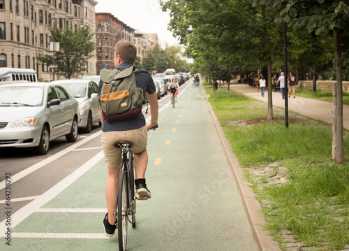 Back view of modern hipster man riding bike on bike lane in the city