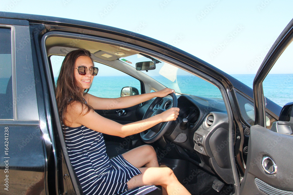 A woman sitting inside a rented car with a sea view A woman sitting inside a rented car with a sea view