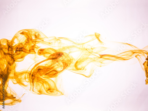 Ink swirl in a water on color background. The paint splash in the water. Soft dissemination a droplets of colored ink in water close-up. Abstract background. Explosion of splashes acrylic ink.