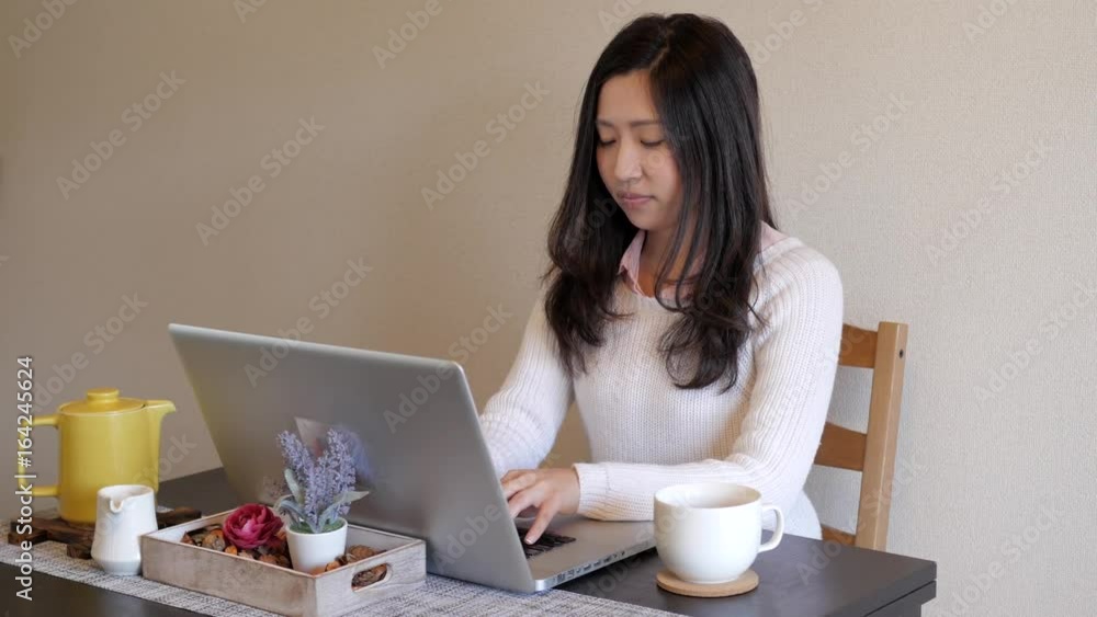 Cute Japanese girl on her computer drinking her tea, coffee Cute Japanese girl on her computer drinking her tea, coffee