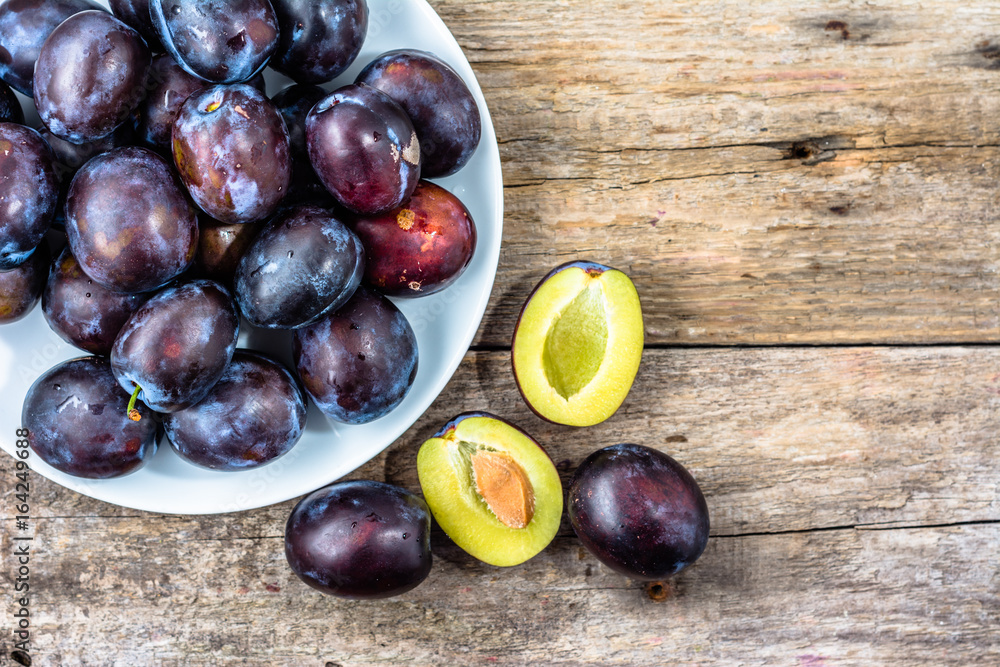 Purple plums on wooden table, autumn seasonal fruits harvest Purple plums on wooden table, autumn seasonal fruits harvest