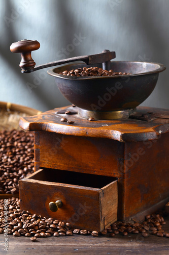 Old coffee grinder and roasted coffee beans on wooden table