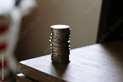 Silhouette of coins and money bank on work desk closeup window background