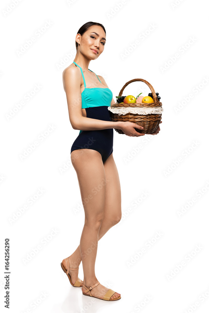beautiful asian woman in swimsuit holding basket with fruits, isolated on white beautiful asian woman in swimsuit holding basket with fruits, isolated on white