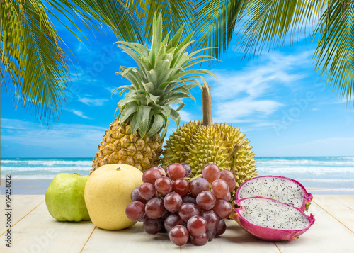 Fruit on wood table against blurred beach background. Summer concept,