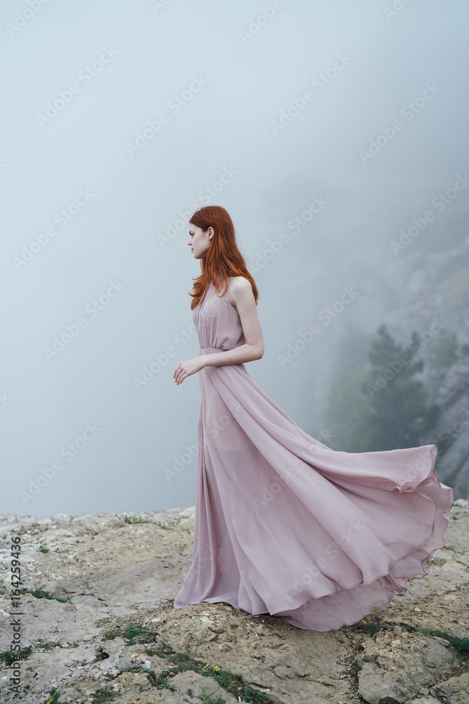 Beautiful young woman in a long dress on a mountainside
