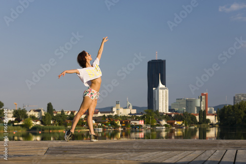 Female dancer at a river with city skyline in the back