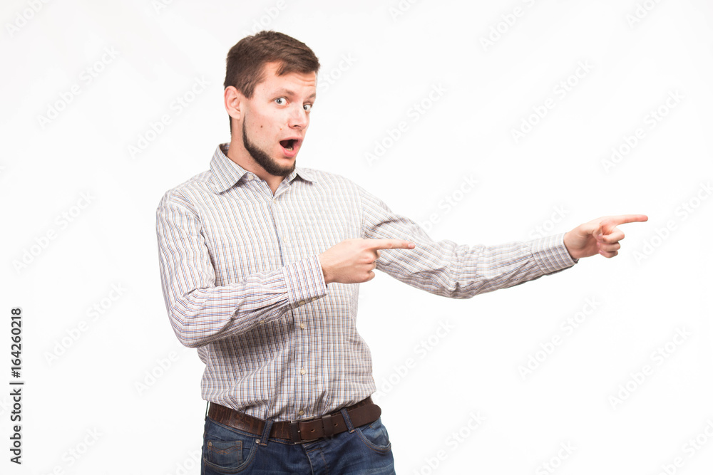 Young surprised man portrait of a confident businessman showing presentation, pointing paper placard gray background. Ideal for banners, registration forms, presentation, landings, presenting concept. Young surprised man portrait of a confident businessman showing presentation, pointing paper placard gray background. Ideal for banners, registration forms, presentation, landings, presenting concept.