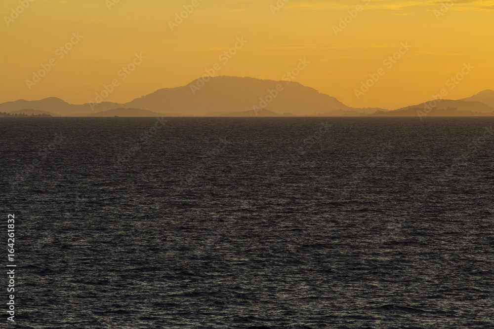 Sea at sunset with mountain scene.