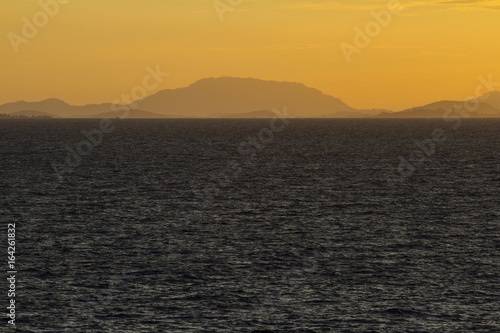 Sea at sunset with mountain scene.