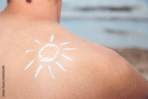 Lotion man with sunscreen with sun over sea background