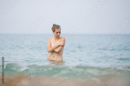 Skinny-Dipping. Young woman stands waist up in sea