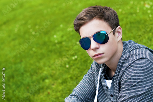 Handsome young man with glasses sitting on the grass