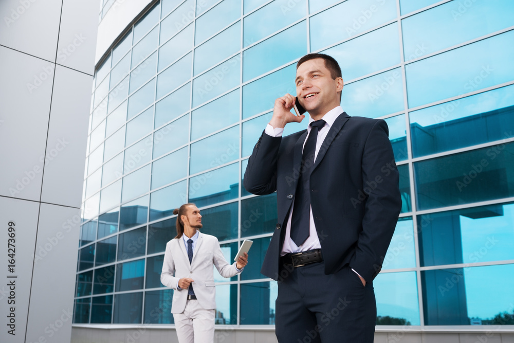 businessman in blue suit talking on the phone in the background of the business center businessman in blue suit talking on the phone in the background of the business center