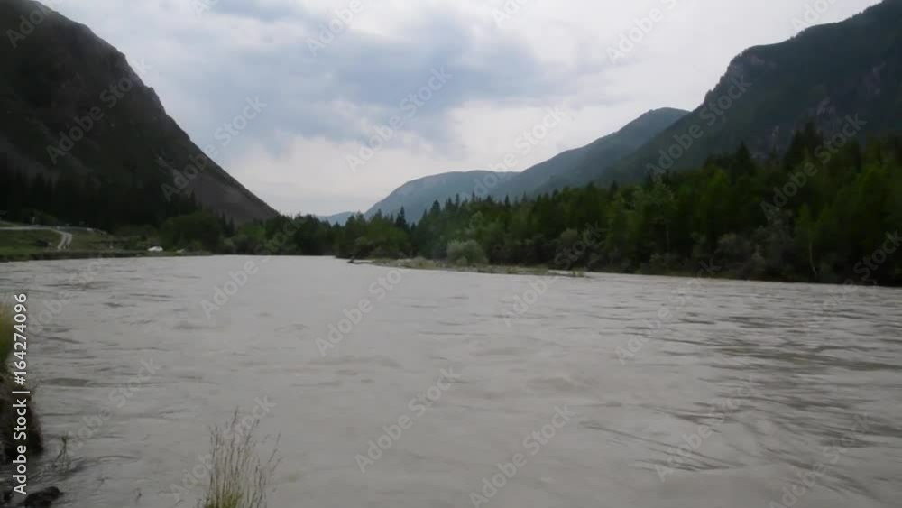Swift water flow in mountain river, rocks along the river bank Swift water flow in mountain river, rocks along the river bank