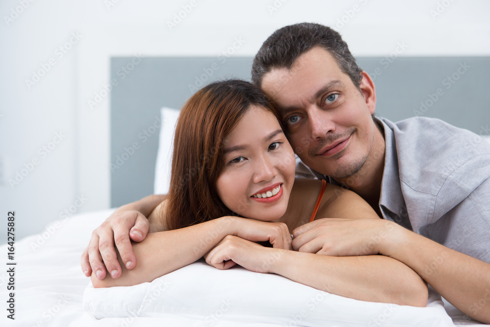 Happy young multiethnic couple lying in bed Happy young multiethnic couple lying in bed