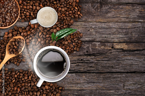Coffee background, top view with copy space. White cup of coffee and milk, ground coffee, coffee beans on dark wooden background © Raewongkhot