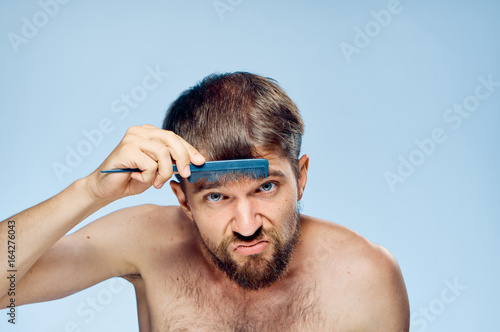 Young guy with a beard on a blue background combing