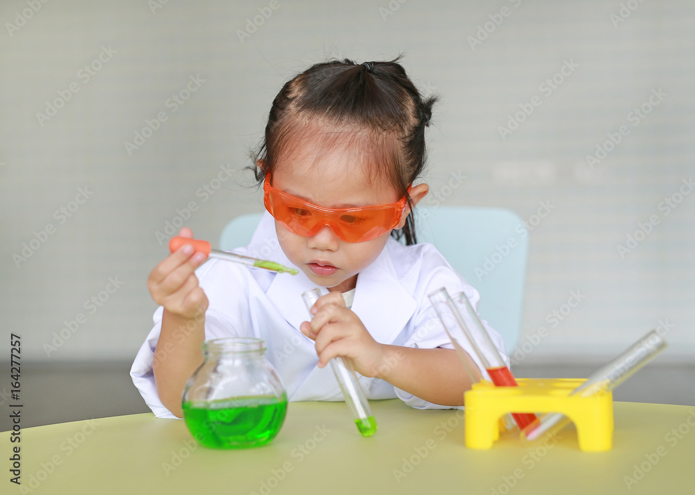 Asian child in scientist uniform holding test tube with liquid, Scientist chemistry and science education concept. Asian child in scientist uniform holding test tube with liquid, Scientist chemistry and science education concept.