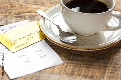 restaurant bill, card and coffee on wooden table background