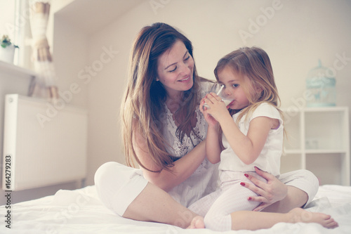 Mother with her daughter enjoying in bed together.