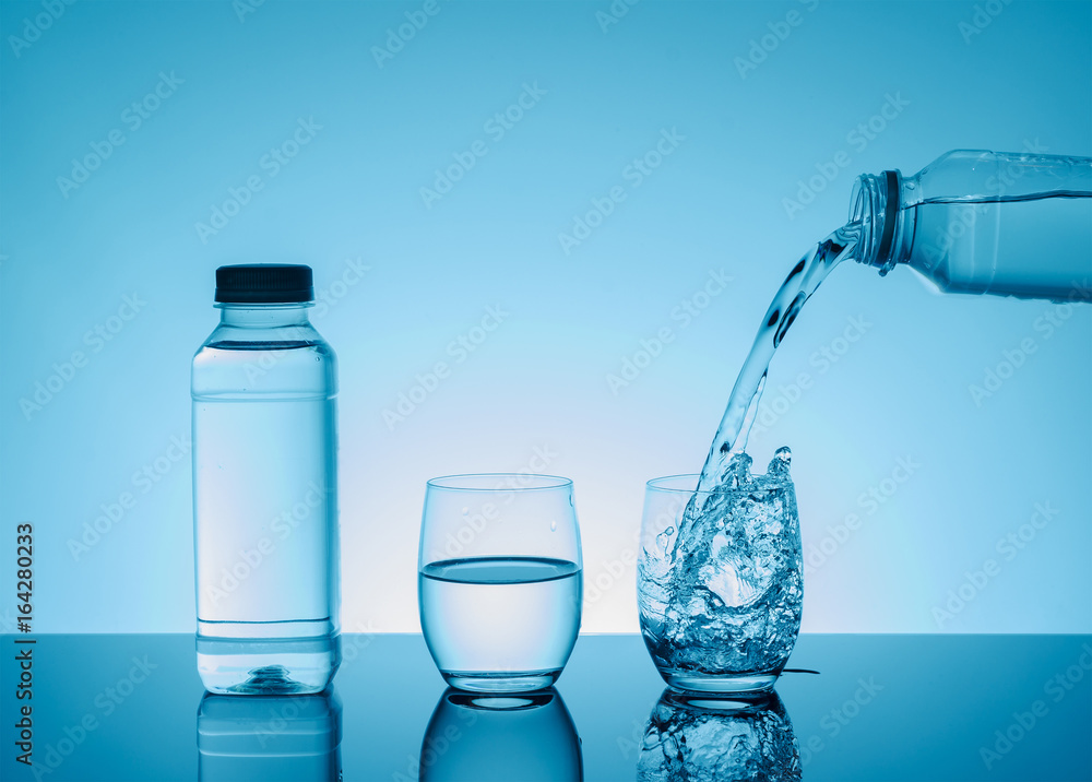 Bottle with creative splashing water in the glass Bottle with creative splashing water in the glass