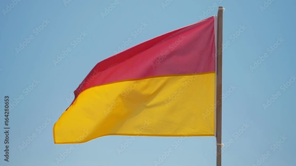Red and yellow beach safety flag against pale sky. Front of the Sun.
Red and yellow beach safety flag against pale sky. Front of the Sun.