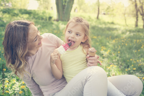 Mother and daughter in the meadow with ice cream.
