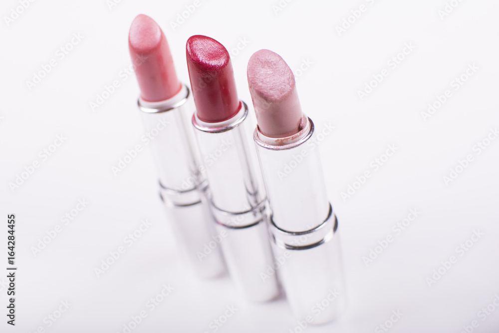 Close up look at lipsticks over a white background. Beauty and makeup concept. Colorful frame with various makeup products on a white background. Close up look at lipsticks over a white background. Beauty and makeup concept. Colorful frame with various makeup products on a white background.