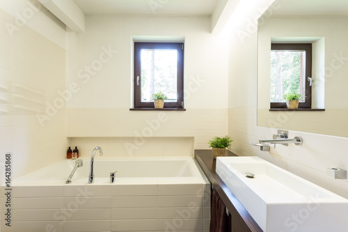 Modern white bathroom with tiled bathtub