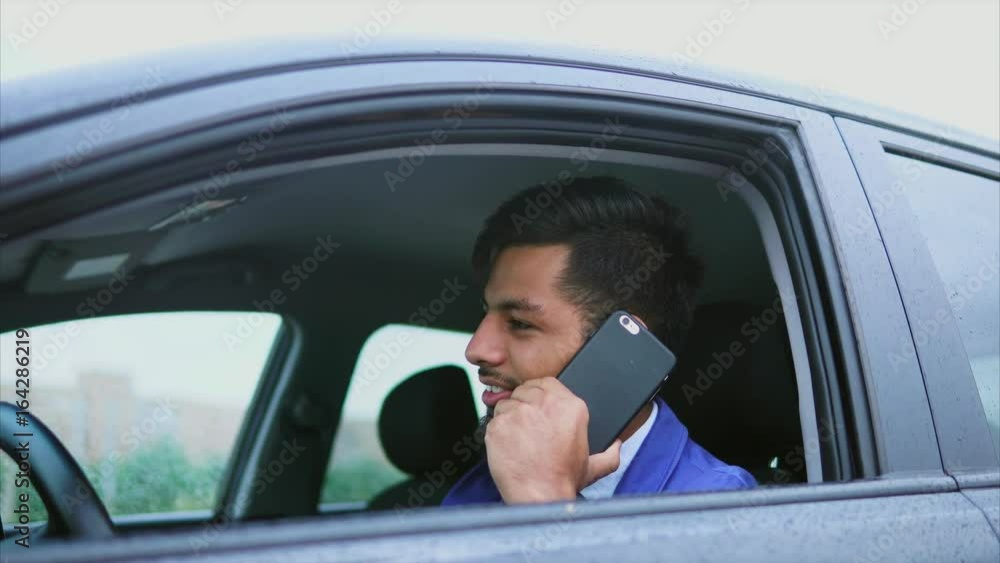Muslim man driving the car and standing in traffic jam. Man while he talking on smartphone. Muslim man driving the car and standing in traffic jam. Man while he talking on smartphone.