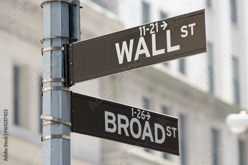 Wall Street and Broad Street corner sign near Stock Exchange, financial district in New York in a sunny day