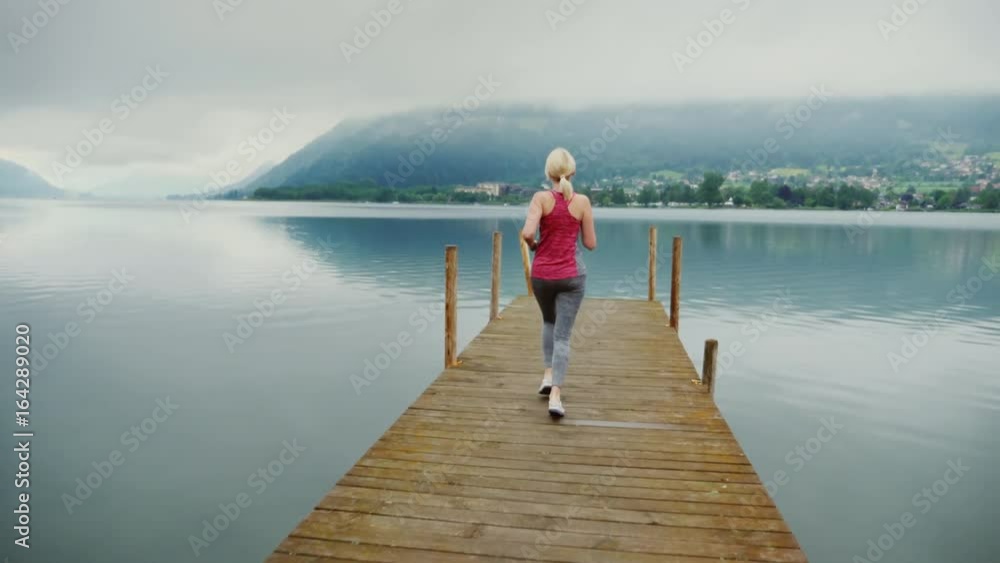 Morning in the Alps near the mountain lake. A woman makes a snap on a wooden pier Morning in the Alps near the mountain lake. A woman makes a snap on a wooden pier