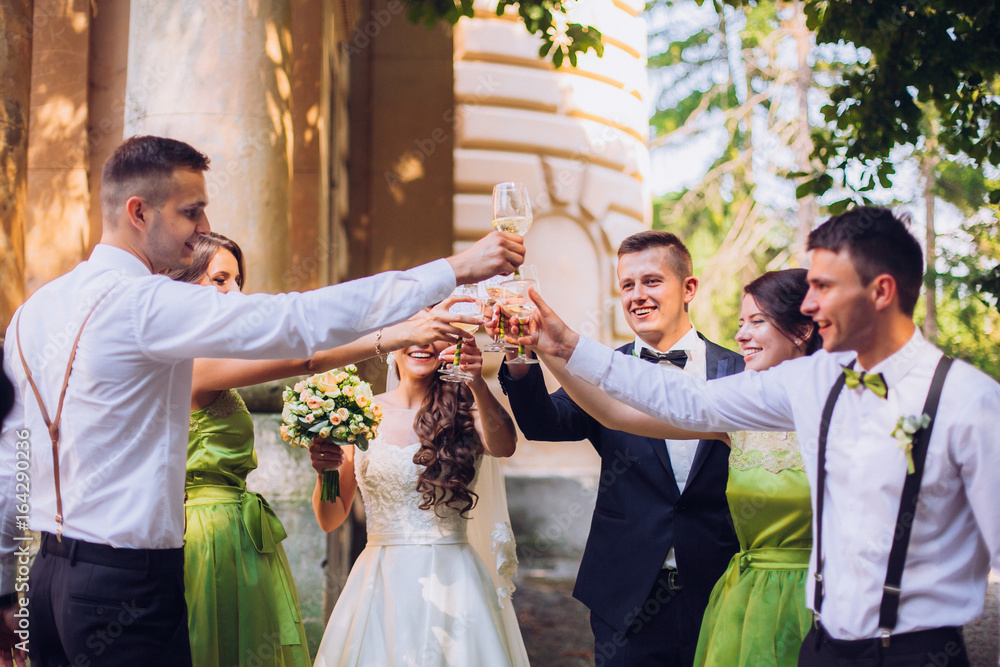 Stylish wedding couple, groomsman and bridesmaids with champagne explosion.