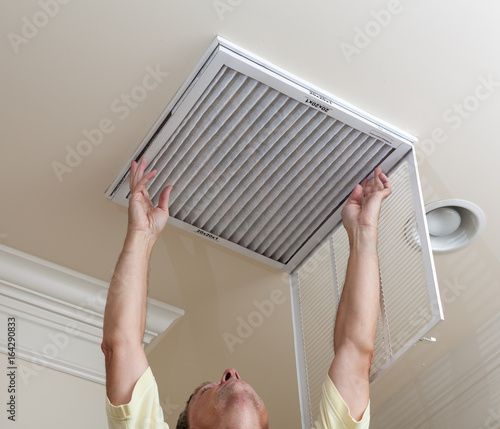 Canvas Print Senior man opening air conditioning filter in ceiling
