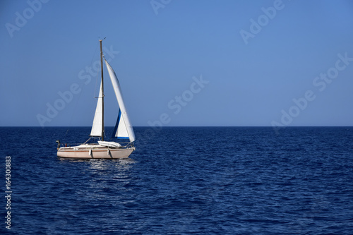 Peaceful afternoon, white sailboat at calm blue sea © Didi Lavchieva