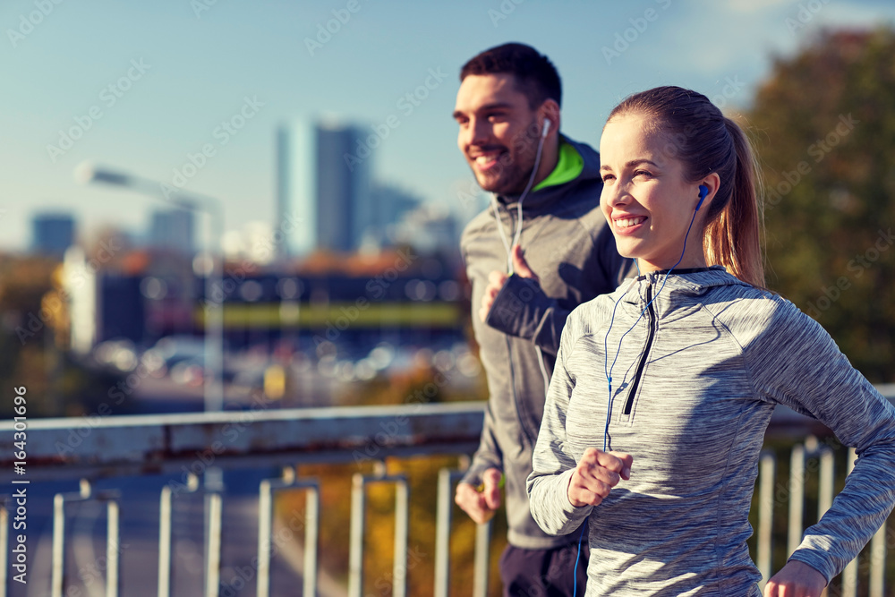 Fototapeta premium happy couple with earphones running in city