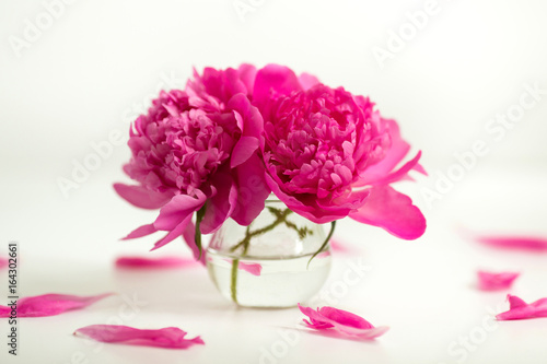 Transparent vase with pink peonies on a white background
