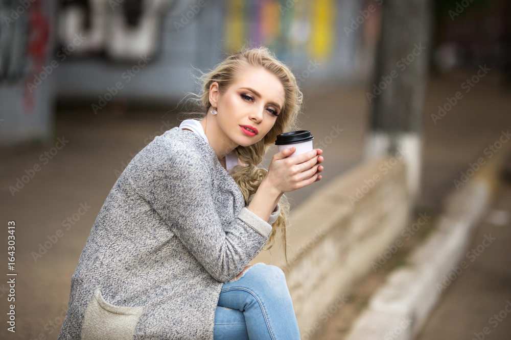 Beautiful sad girl drinking coffee on the street