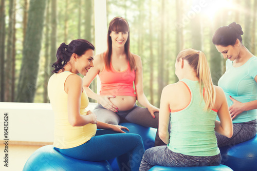happy pregnant women sitting on balls in gym © Syda Productions