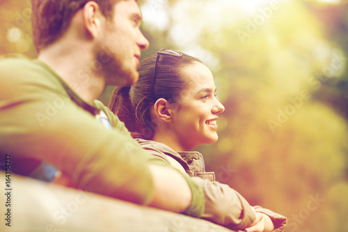 smiling couple with backpacks on bridge in nature