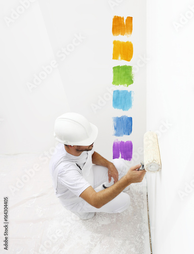 painter man with paint roller painting color samples, top from view isolated on blank white wall background