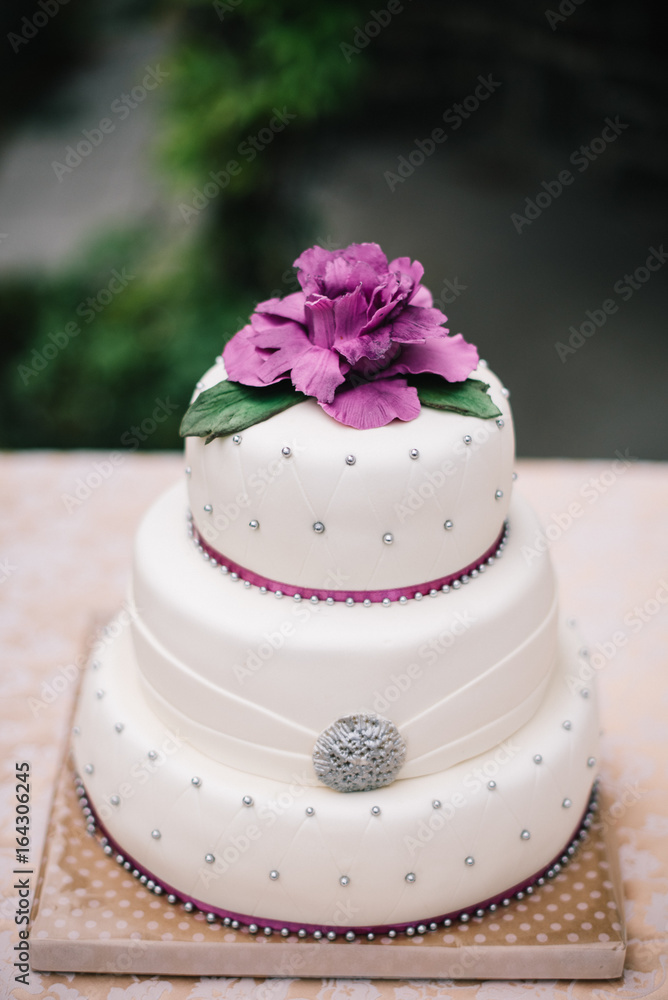 Weding cake with purple peony on top with silver dots Weding cake with purple peony on top with silver dots