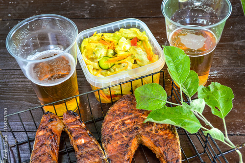 Grilled salmon steak. Glass with beer. Cabbage salad. Picnic in nature photo