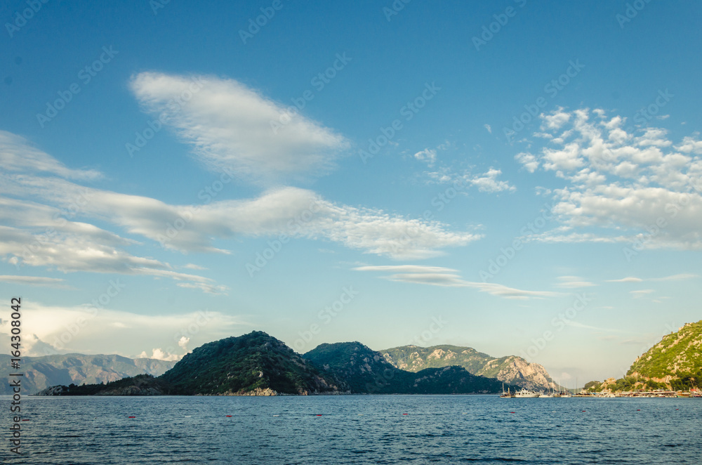 Summer panorama of the beach at sea and high mountains 