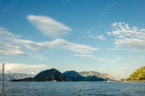 Summer panorama of the beach at sea and high mountains 