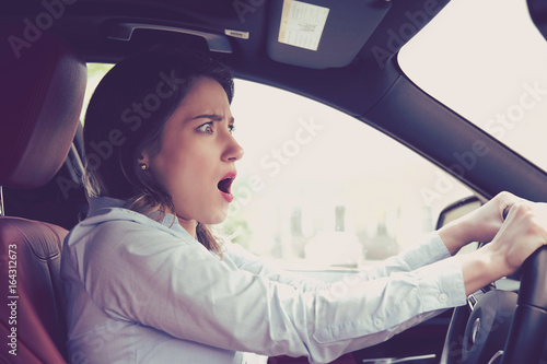 Young woman driving a car shocked about to have traffic accident