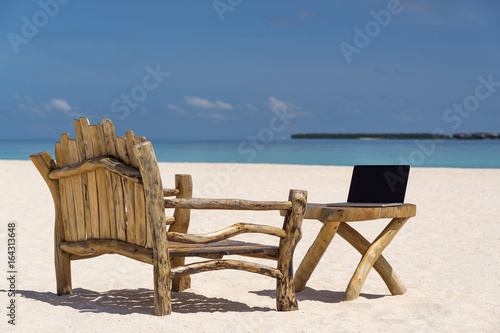 laptop blank screen on wooden desk with beach. relax concept.