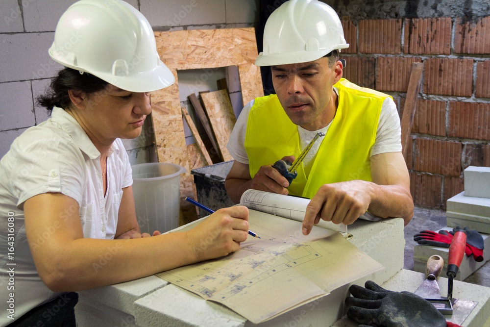 The female engineer shows the construction project to the head of the building site The female engineer shows the construction project to the head of the building site